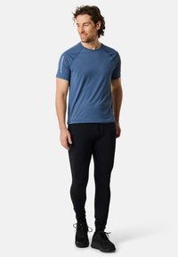 Blaues kurzärmliges Sportshirt kombiniert mit schwarzen Leggings. Das Shirt hat eine glatte Textur, während die Leggings ein figurbetontes Design mit einer seitlichen Tasche aufweisen.