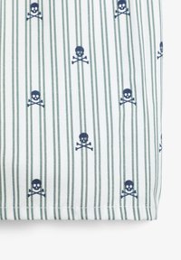 Tela a rayas con un patrón repetido de calaveras y tibias cruzadas en azul marino sobre fondo blanco con rayas verdes. Textura suave, mezcla de algodón.