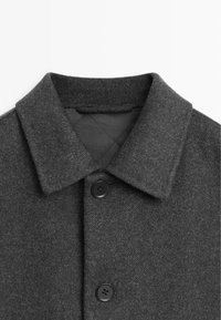 Gray wool coat featuring a notched collar, two black buttons, and a herringbone texture. Interior has a quilted lining.