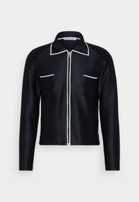 Svart långärmad zip-up jacka med vitt kantband på kragen, dragkedjan och bröstfickorna, tillverkad av strukturerad tyg.