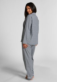 Zwart-wit geblokte pyjama's bestaande uit een langarmige knoopsluiting bovenstuk en bijpassende losse broek met een ontspannen ontwerp en een gladde textuur.