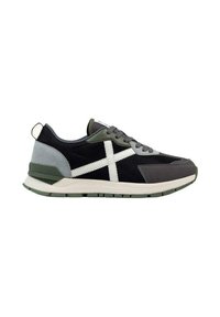 Zapatilla deportiva en negro y gris con acentos en verde, materiales de textil y gamuza, un logo cruzado blanco y una suela acolchada con agarre texturizado.