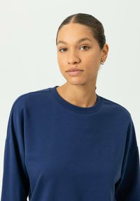 Marineblauwe sweatshirt met een ronde hals, lange mouwen en een losse pasvorm. Gemaakt van zachte stof met een gladde, egale textuur.