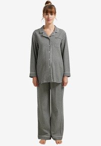 Black and white checkered pajama set, featuring a button-down top with a pocket and loose-fitting pants, made of soft fabric.