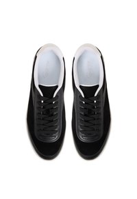 Czarne zamszowe sneakersy z gładkim skórzanym noskiem, płaskimi czarnymi sznurowadłami i białym wyściełanym wnętrzem. Minimalistyczny design bez widocznych logo.