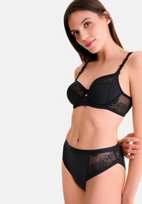 Ensemble de lingerie noire comprenant un soutien-gorge rembourré avec superposition en dentelle et bretelles décoratives, accompagné d'une culotte taille haute avec des accents en dentelle.