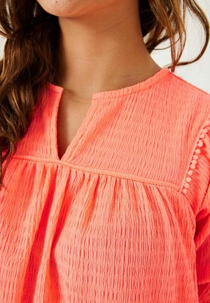 Top de tela fruncida color coral con escote en forma de ojete, cuerpo fruncido y detalles texturizados. Presenta detalles decorativos a lo largo de la costura del hombro.