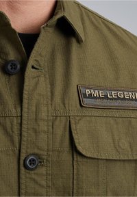 Camicia verde oliva in tessuto testurizzato, con chiusura a bottoni, taschino e etichetta di marca con la scritta "PME Legend American Classic."