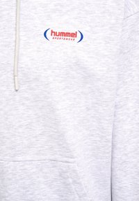 Hoodie gris clair en tissu doux, avec une poche avant, une capuche à cordon et un logo "hummel sportswear" rouge et bleu.