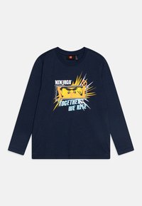 Tamno plavi dugih rukava majica s vibrantnom žutom grafikom nindže okruženom detaljima eksplozije i tekstom "ZAJEDNO USTAJEMO" u plavoj boji.