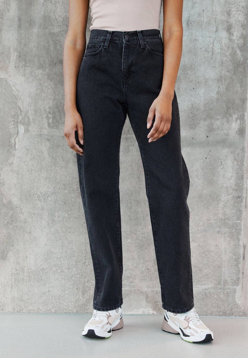 Svarte høytalede jeans med rett ben-design og detaljerte sømmer. Kombinert med hvite og beige joggesko.