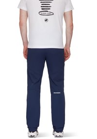 Marineblauwe softshell broek met een getailleerde pasvorm, uitgerust met gebogen knieën, logo-detail op het onderbeen en een soepele stoftextuur.