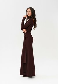 Długa bordowa sukienka z długimi rękawami, dopasowaną górą i zwiewnym dołem. Posiada marszczenie w talii oraz miękką, gładką teksturę.