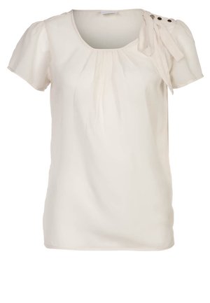 Lyscremet kortærmet bluse med rund hals, samlede detaljer foran, og en sløjfeaccent på venstre skulder med knapbehør.