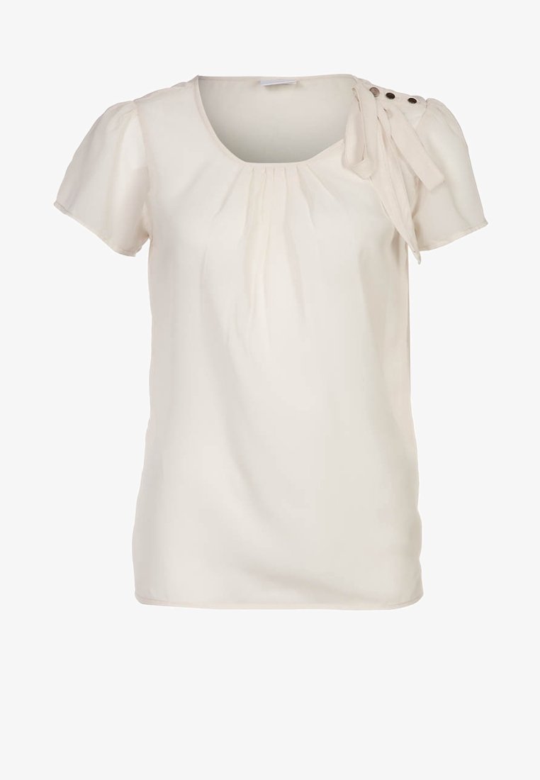 Light cream short-sleeved blouse with a rounded neck, gathered detailing at the front, and a bow accent on the left shoulder with button embellishments.