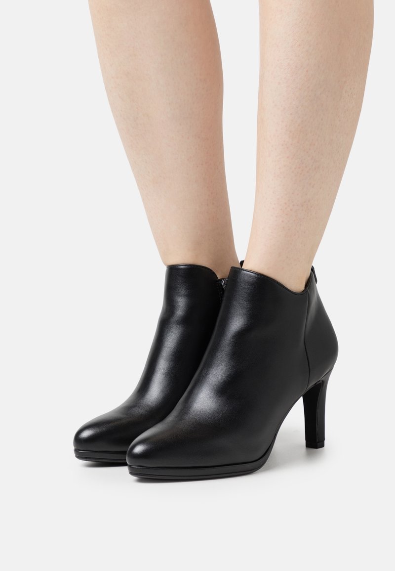 Bottes chevilles en cuir noir à texture lisse, bout pointu et talon de 7,5 cm, avec une fermeture éclair latérale pour un port facile.