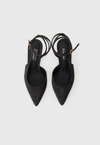 Μαύρες γόβες με αιχμηρή μύτη και σλίγκ μπλούζες, με υφασμάτινη επένδυση από ριχναστάρι, λεπτές γονατίες και ομαλό μαύρο εσωτερικό.