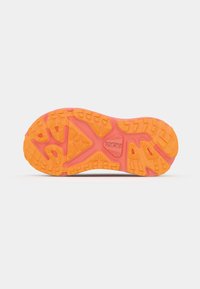 Sole of a sports shoe, featuring a textured, multicolored design with shades of orange and pink, and a patterned tread for traction.