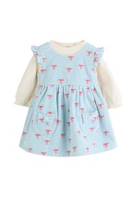 Svetlomodra kordurova obleka z rdečimi vzorci pentelj, ramenskimi trakovi z volančki in dvema sprednjima žepoma. Prekrita s kremno dolgo majico z dolgimi rokavi.