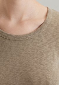 Khaki short-sleeve t-shirt with a crew neck, made from a soft, textured fabric, featuring a subtle heather pattern and reinforced seams.