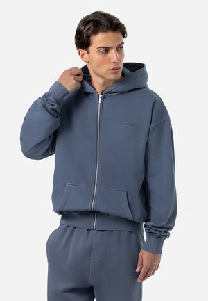 Hooded, zip-up sweatshirt in soft blue fabric with a kangaroo pocket and ribbed cuffs. Features subtle logo detail on the chest.