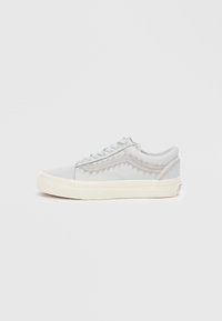 Adidași gri cu un design texturat, talpă din cauciuc alb și șireturi plate. Prezintă cusături decorative pe părțile laterale. Stil minimalist.