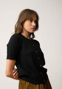 Svart kortärmad cardigan i mjukt tyg, med knappstängning framtill och rundad halsringning.