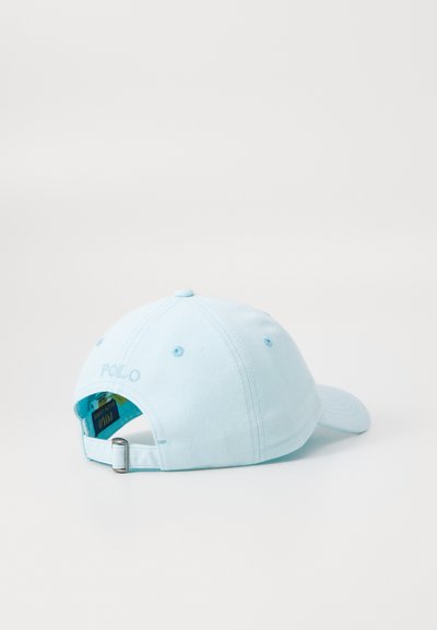 Lys blå baseballcaps laget av bomull, med justerbar stropp, brodert "POLO"-logo og ventilasjonsøyer på sidene.