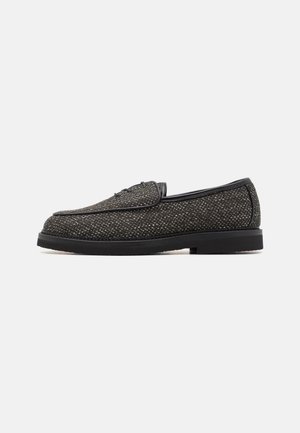 Black slip-on shoes with textured fabric upper, smooth black leather accents, rounded toe, and low rubber sole.
