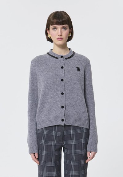 Cardigan grigio lavorato a maglia con collo rotondo, bottoni neri e dettagli con perline sul colletto. Presenta un motivo testurizzato e un orlo corto.