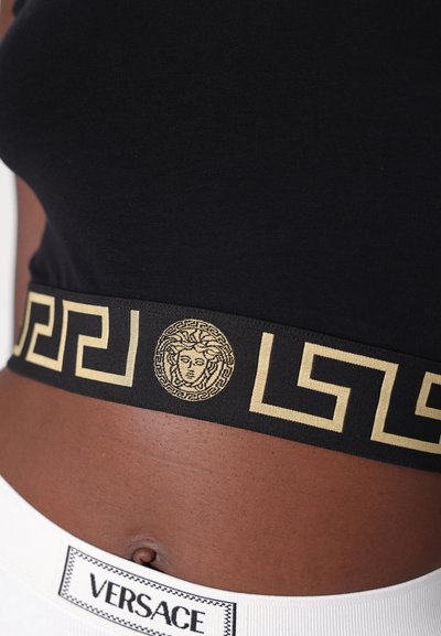 Black elastic bandeau with gold Greek key pattern and Medusa emblem. White band below features "VERSACE" logo. Smooth texture.
