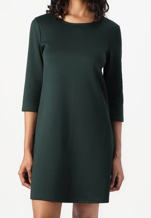 Robe vert foncé longueur genou avec manches trois-quarts et encolure ronde. Confectionnée en tissu lisse et extensible avec un design simple.