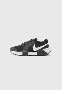 Nike atletske cipele s crnim mrežastim gornjištem, teksturiranim detaljima, bijelim swoosh logotipom i bijelom i crnom potplatom s rebrastim uzorkom.