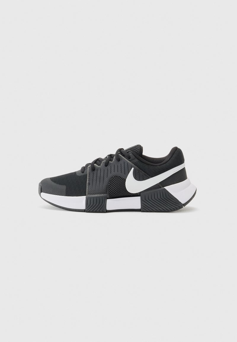 Sapatos desportivos Nike com um cabedal em malha preta, detalhes texturizados, logotipo swoosh branco e uma sola em preto e branco com um padrão estriado.