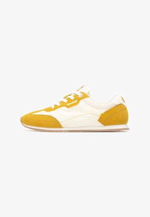 Zapatillas retro en amarillo y blanco que combinan materiales de ante y cuero, con puntera redondeada, detalles texturizados y cordones blancos.