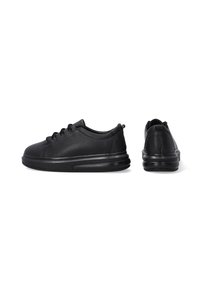 Schwarze Sportschuhe haben ein strukturiertes Obermaterial mit Perforationen, eine abgerundete Spitze und eine dicke schwarze Sohle für Dämpfung.