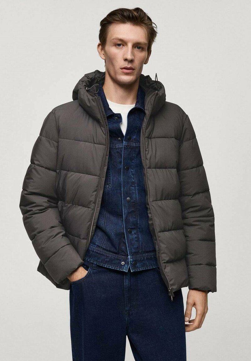 Grå pufferjacka med huva, med ett vadderat mönster och framzipper. Bärs över en blå denimskjorta och mörka denimbyxor.