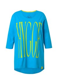 Türkisfarbene Baumwoll-T-Shirts mit drei Viertelärmeln, mit großen gelben Buchstaben "HYGGE" auf der Vorderseite und einem gelben Akzent am Kragen.