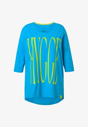 Turkusowa bawełniana koszulka z rękawami do trzech ćwiartek, z dużym żółtym napisem "HYGGE" z przodu oraz żółtym akcentem przy dekolcie.