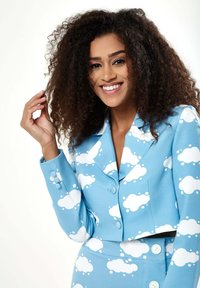 Blue cropped blazer with large white cloud pattern, featuring a notched lapel and two buttons; coordinated high-waisted skirt.