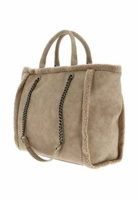 Sac cabas beige en suédine synthétique avec bordure en shearling duveteux, doubles poignées courtes et détails à chaîne noire sur les côtés.