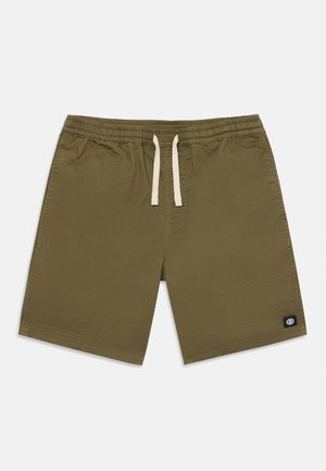 Lyhyt oliivinvihreä housu, jossa on joustava vyötärö, kermanvärinen nauha ja pieni musta logo-patch ala oikeassa kulmassa.