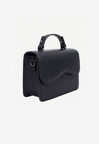 Sac à main en cuir noir avec un rabat incurvé, une poignée supérieure et un anneau métallique sur le côté pour attacher une bandoulière.