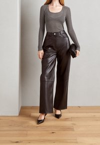 Pruhovaný elastický top s dlouhým rukávem a širokým výstřihem; černé kožené kalhoty s širokými nohavicemi; čern�é psaníčko; černé boty s špičatou špičkou.