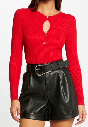 Haut rouge à rayures côtelées à manches longues avec une découpe en trou de serrure et une fermeture à bouton, assorti à un short en simili cuir noir taille haute et une ceinture noire.