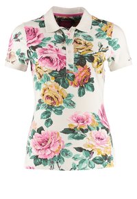 Polo shirt floral avec une base blanche, des motifs de roses colorés en rose, jaune et vert, avec un col et une patte de boutonnage à trois boutons.