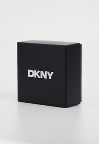 Scatola rettangolare nera con una superficie liscia, caratterizzata da un logo bianco "DKNY" ben visibile sul davanti. Design minimalista, senza ulteriori motivi.