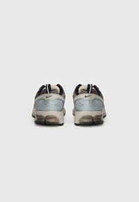 Baskets Nike avec une tige en tissu beige, des détails en maille, des accents bleu clair et un contre-langue texturé. Grand amorti et semelle en caoutchouc.
