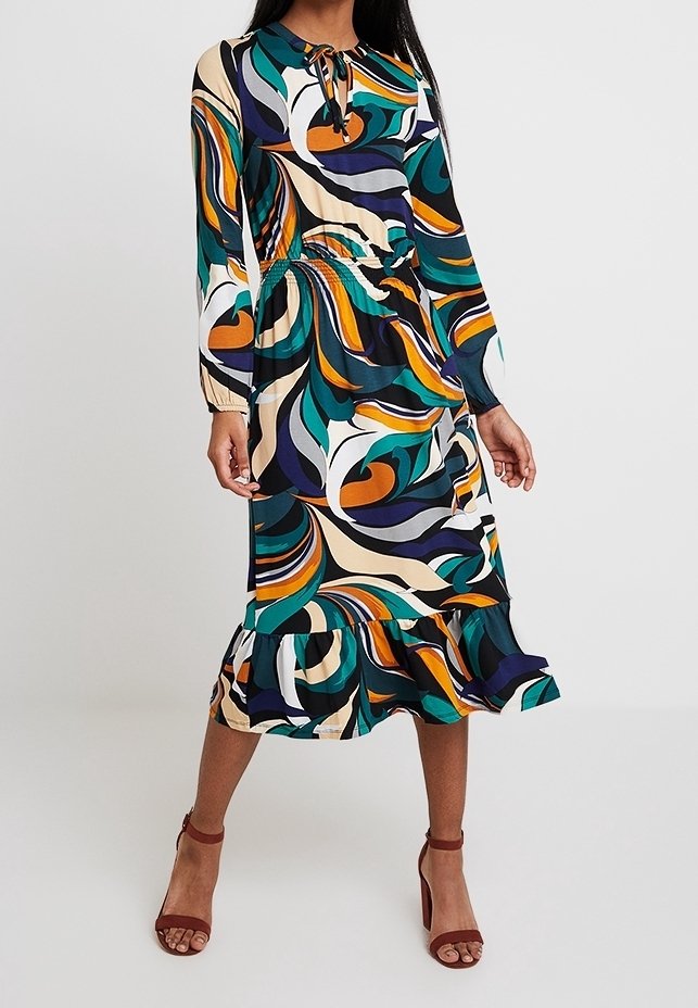 Sukienka z długim rękawem, dopasowaną talią, rozszerzającym się dołem i wielokolorowym wzorem w spirale w odcieniach zieleni, pomarańczu, fioletu i beżu. Lekki materiał.