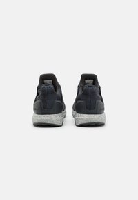 Black textured sneakers with padded heels, featuring a gray speckled midsole and black accents on the tongue and collar.